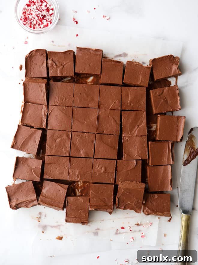 Neatly cut squares of homemade peppermint fudge, showcasing its smooth texture and rich color, arranged on a cutting board, ready for serving.