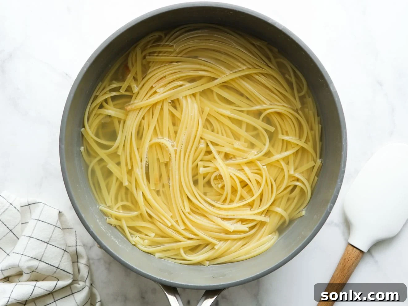 Al dente pasta strands freshly cooked in a large pot, ready to be drained and mixed with sauce.