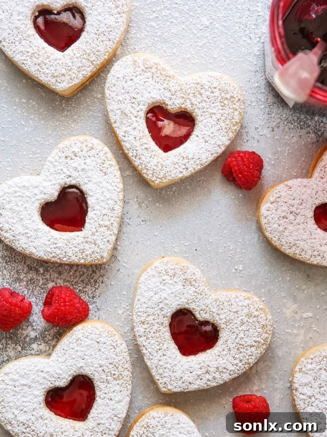 Delicate Raspberry Almond Linzer Cookies with a cut-out center, showcasing a luscious raspberry jam filling.