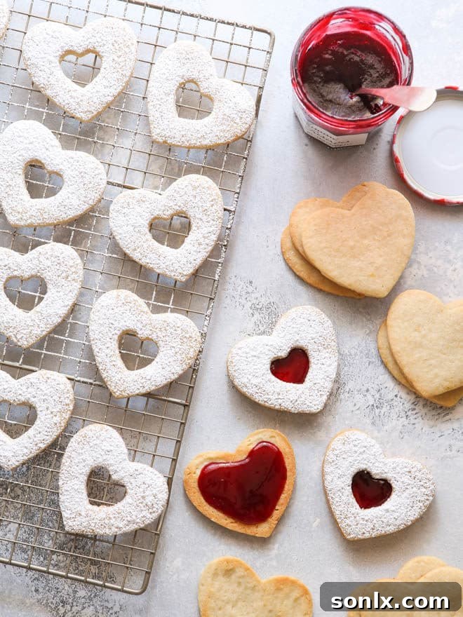 A stack of beautifully assembled Raspberry Almond Linzer Cookies, dusted with powdered sugar and ready to be enjoyed.
