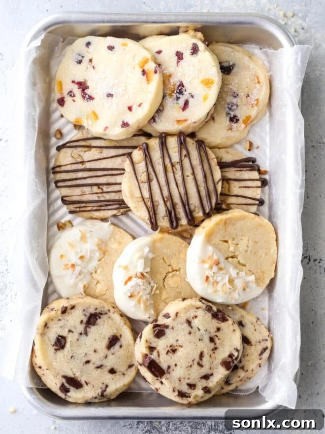 Four varieties of classic shortbread cookies on a single baking tray, showcasing different shapes and toppings like chocolate drizzle and sprinkles.