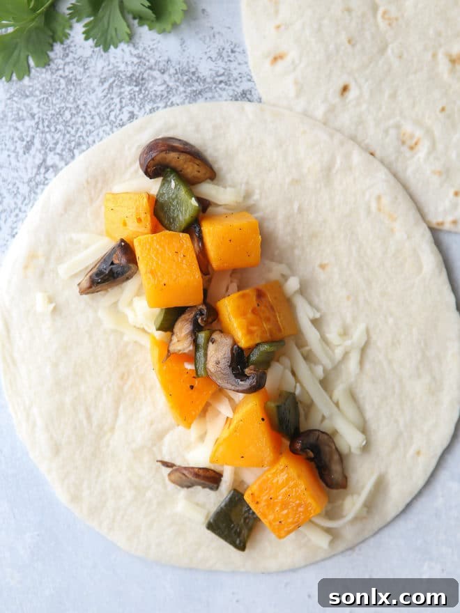 Hands assembling butternut squash, mushroom, and poblano enchiladas in a casserole dish.