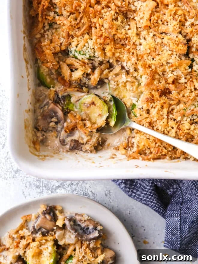 scooping brussels sprout and mushroom casserole out of baking dish, highlighting its creamy texture and crispy topping