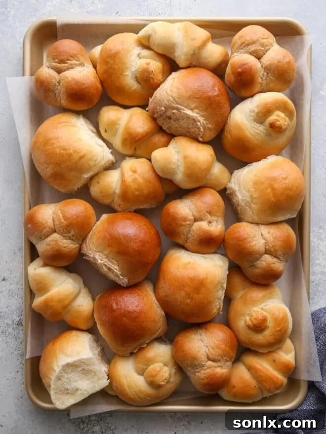 Flour Power: The Science Behind Perfect Baking 6 A sheet pan filled with various shapes and flavors of freshly baked dinner rolls, showcasing a golden-brown crust