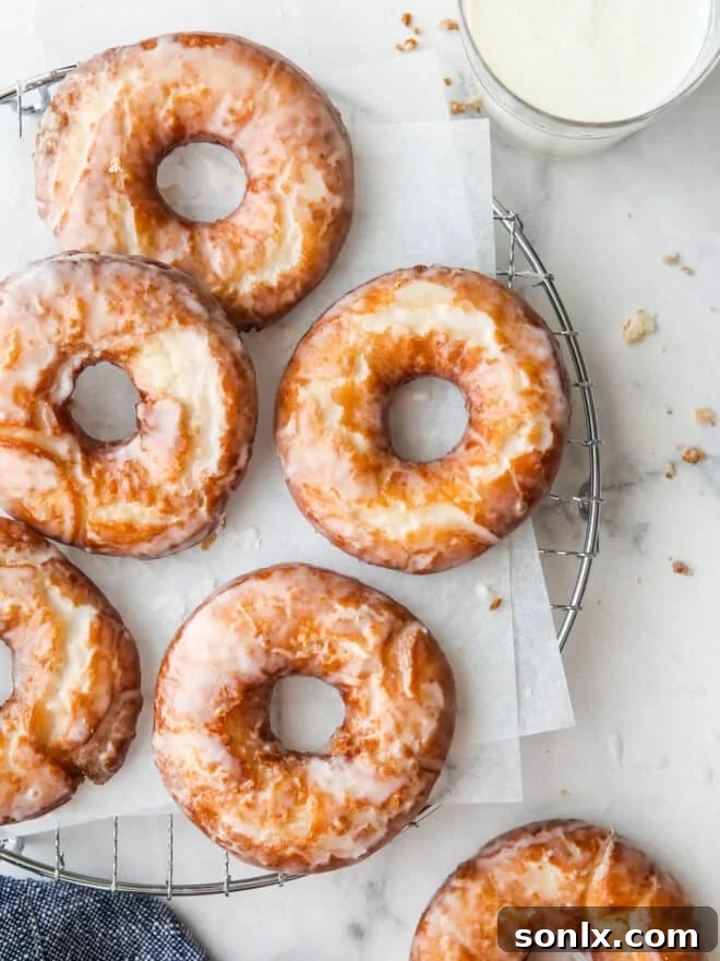 glazed old fashioned doughnuts on a wire rack with glass of milk
