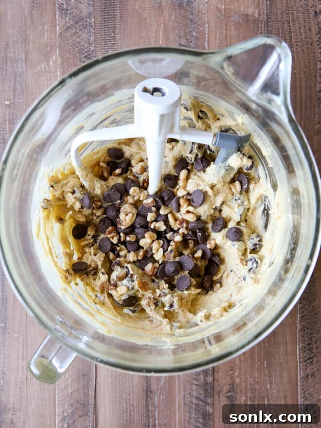 Cookie dough being mixed in an electric mixer bowl, showcasing the rich, creamy texture before adding chocolate chips.