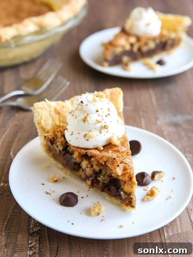 Close-up of a perfectly baked Toll House Cookie Pie, sliced and served with whipped cream, highlighting its warm, gooey center.