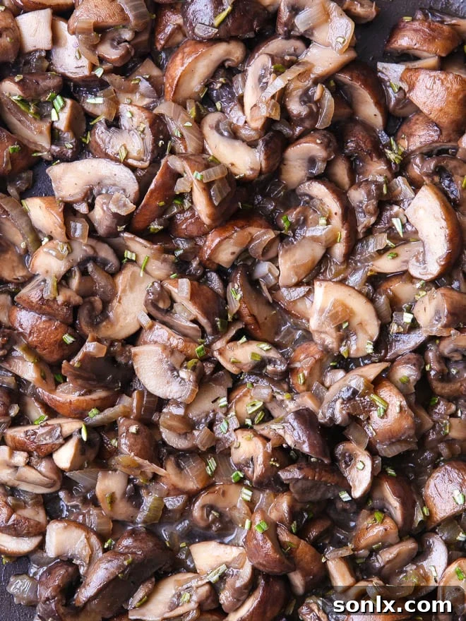 Close-up shot of perfectly sautéed mushrooms, shallots, and fresh rosemary in a skillet, showcasing the rich brown color and fragrant herbs before mixing into the tart filling.