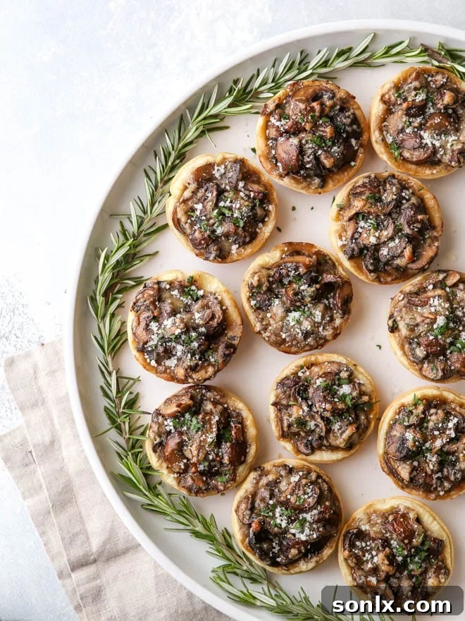A stunning close-up of baked mini mushroom puff pastry tarts on a beautiful serving platter, showcasing their golden crust and savory filling, ready to be enjoyed.