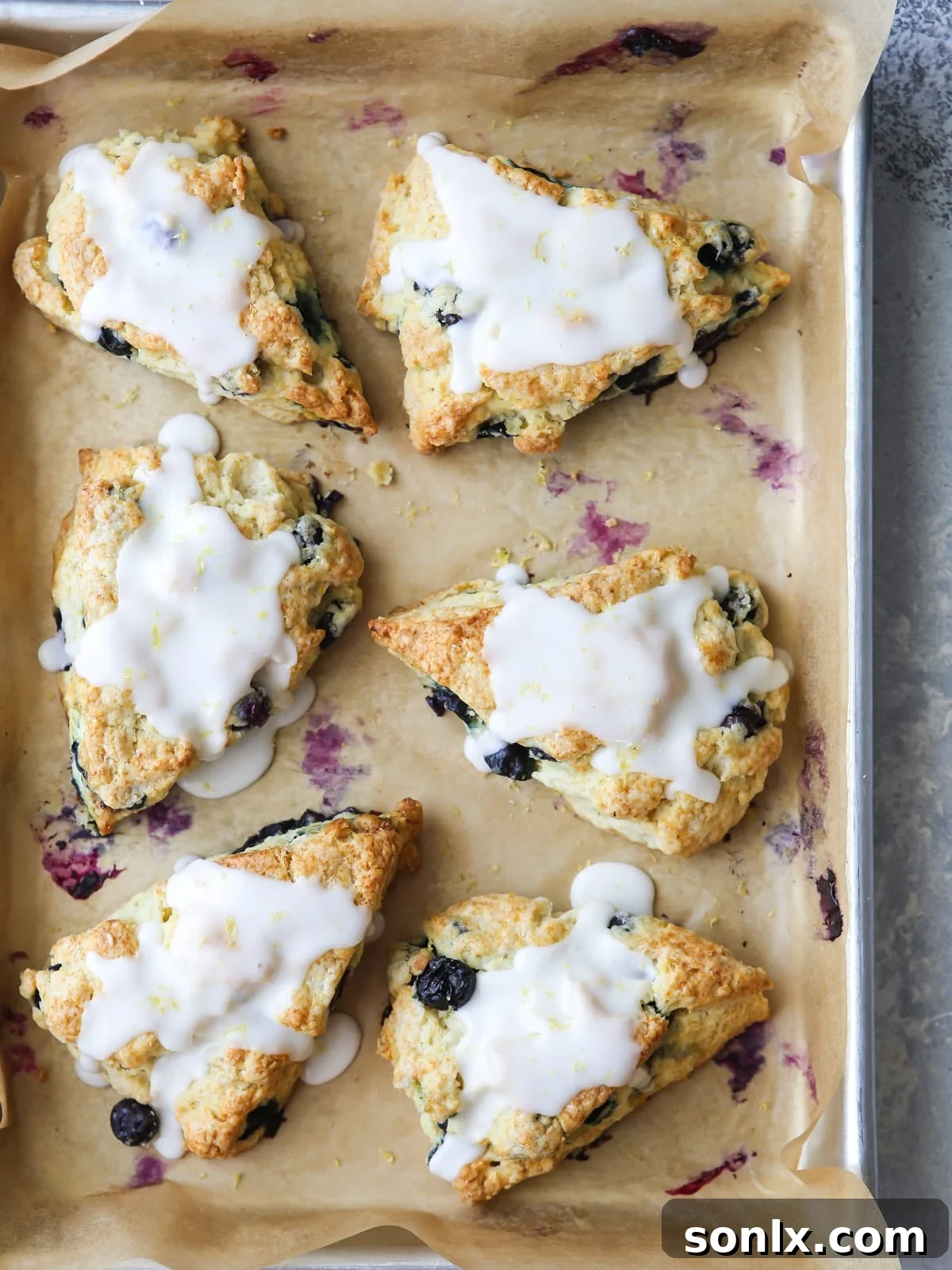 Lemon glaze being drizzled over warm lemon blueberry scones