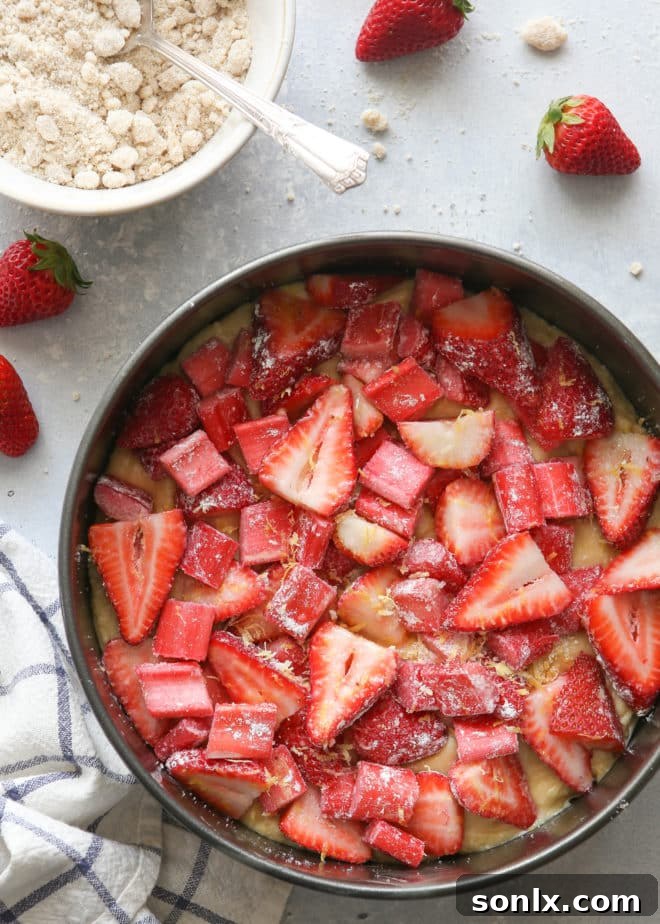 Hands preparing the layers of strawberry rhubarb coffee cake