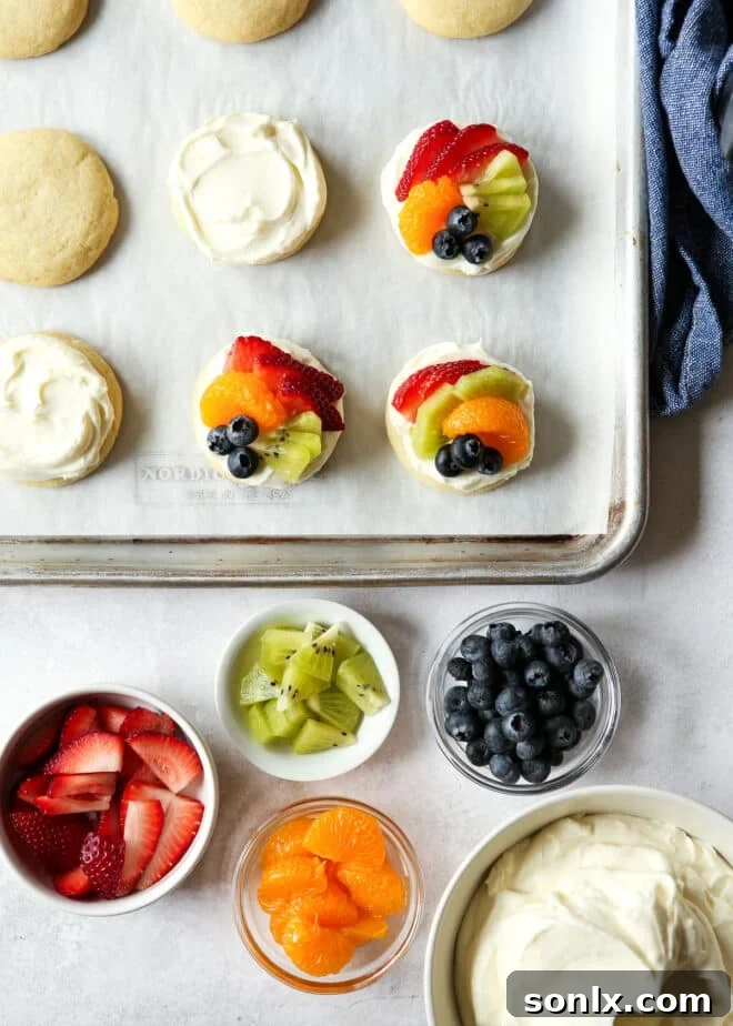 assembling sugar cookie fruit pizzas with bowl of fruit