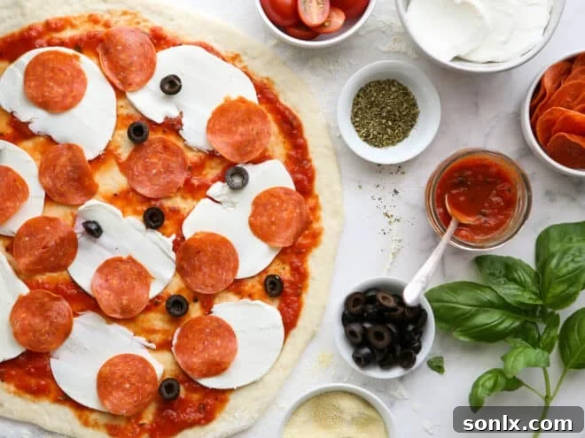 assembling pizza with cheese, pepperoni and olives with prepped toppings on the side