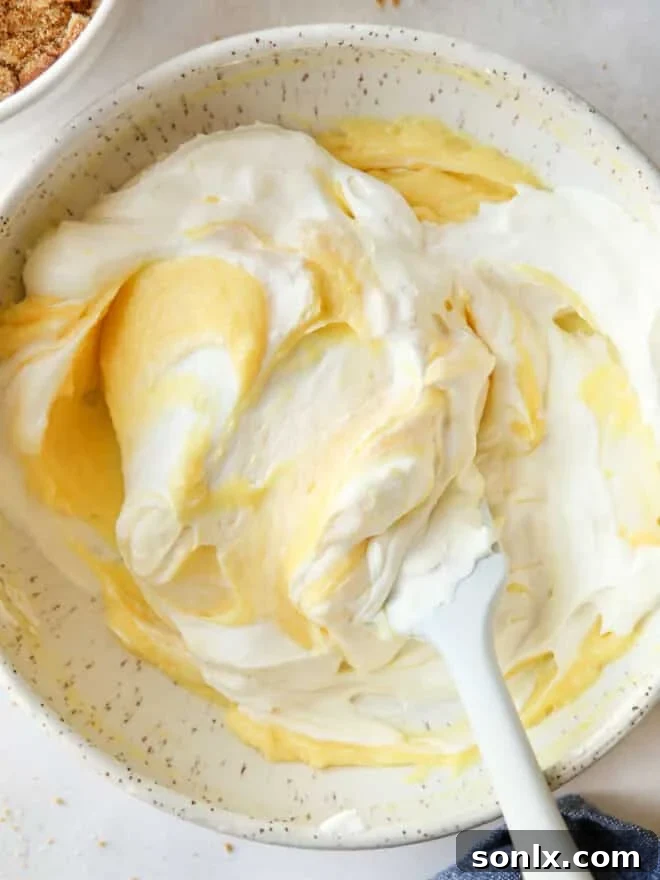 folding whipped cream into vanilla pudding in a bowl