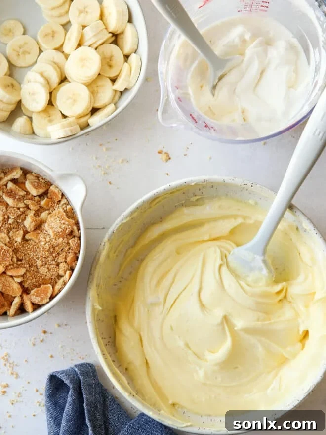 everything needed to assemble banana pudding cups: crushed wafers, sliced bananas, whipped cream and vanilla pudding